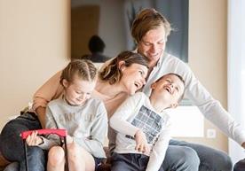 Una famiglia felice composta da due adulti e due bambini nel soggiorno di un appartamento vacanze