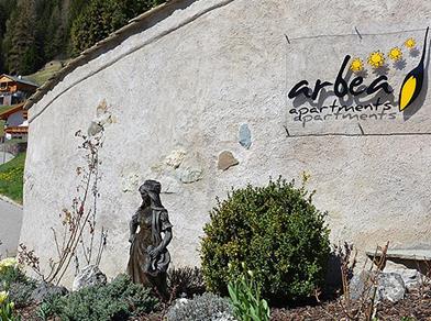 Vista di un giardino con una piccola statua di una donna in costume tradizionale davanti a un muro con l'insegna 