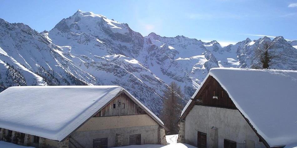 Due baite innevate davanti a uno spettacolare panorama alpino sotto il sole splendente.