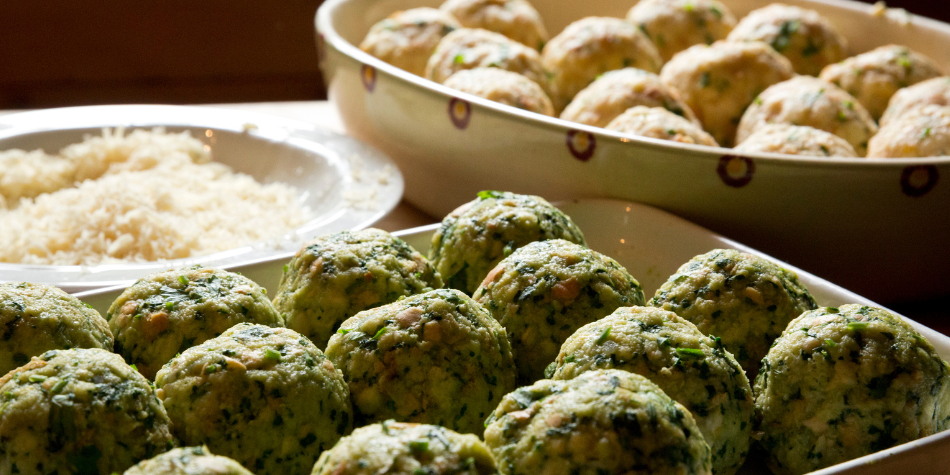 Frisch zubereitete Spinat- und Käseknödel auf einem Tablett, bereit zum Kochen.