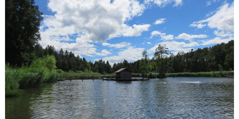 Völser Weiher lake under a blue sky with white clouds